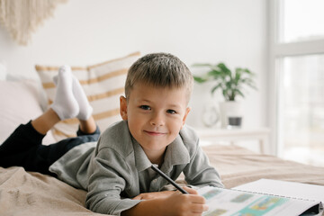 Caucasian boy studing from home. Cute boy 7 years old writing in a workbook. Online education - 487260255
