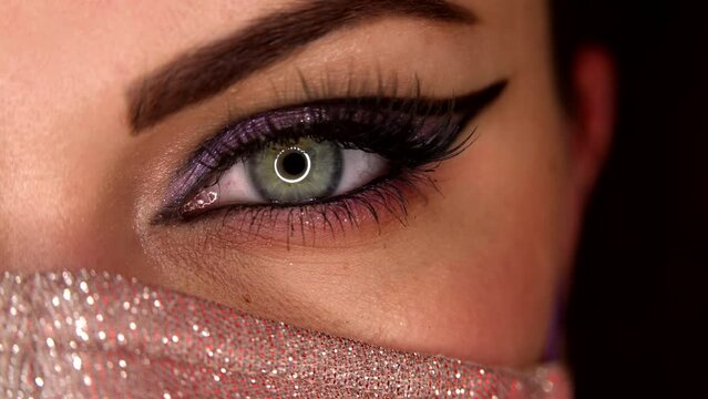 Lady in glitter protective mask. Macro. Glitter shadows and false lashes. Woman eye with fancy arrow make-up. Girl, green eye. Pandemic, covid-19 concept.