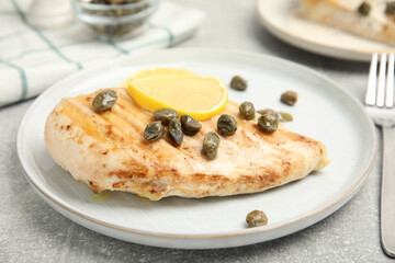 Delicious chicken fillet with capers and lemon served on light grey table, closeup