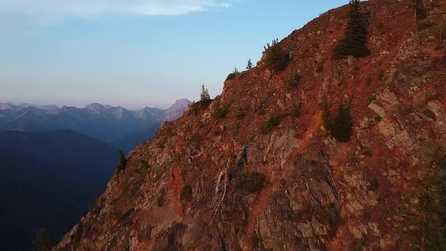 Golden hour light covering the mountain, aerial shot with background reveal