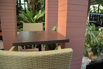 Minimal decoration with weave chair and simply table set. And all ornamental tree on around.