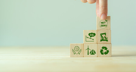 Net zero and carbon neutral concept. Net zero greenhouse gas emissions target. Climate neutral long term strategy. Putting wooden cubes with green net zero icon and save world icon on grey background. - obrazy, fototapety, plakaty
