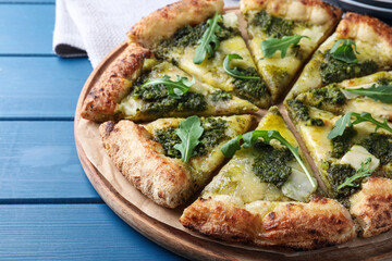 Delicious pizza with pesto, cheese and arugula on blue wooden table, closeup
