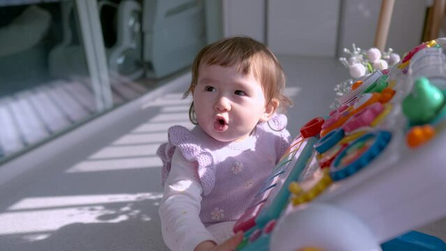 Happy little toddler looking at camera while playing with Theatrical Edutable for early baby development -zoom in