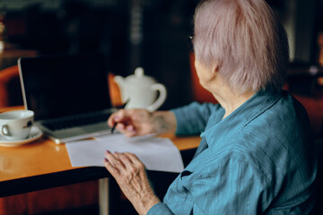 Happy senior woman documents work sheet of paper and pen Freelancer works unaltered