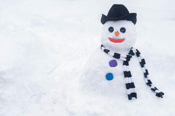 Snowman in a hat and a striped scarf. Winter fun.