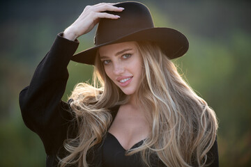 Portrait of young woman outdoor. Romantic girl in fashion brim black hat with beauty face.