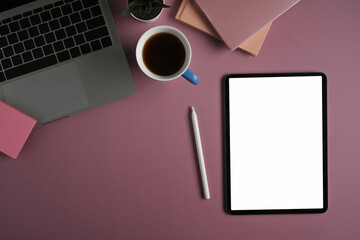 Digital tablet, stylus pen, laptop computer and coffee cup on purple background.