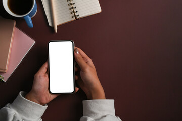 Above view young woman using smart phone on purple background.