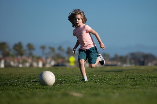 Soccer kids, child boy play football outdoor. Young boy with soccer ball doing kick. Football soccer players in motion. Cute boy in sport action.