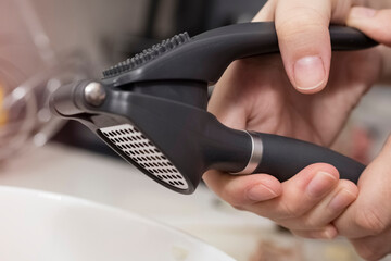 garlic press in the chef's hand. Close-up