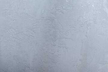 Background of a gray wall with a texture of decorative plaster. The concept of renovation of premises, wall decoration in the interior. Background, texture