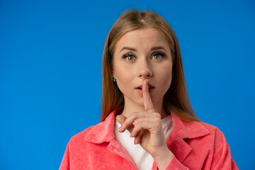 Young pretty woman showing silence gesture over blue background - obrazy, fototapety, plakaty