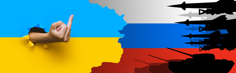 Russian-Ukrainian crisis, conflict.Hand gesture in forme middle finger in a torn paper hole.The concept of rebuffing the aggression of the Russian Federation,threatening Europe with war.Ukrainian flag