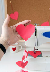 Sewing machine and paper hearts. The process of making a garland. Concept to sew with love, Valentines Day.