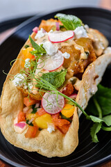 Fish taco with salsa salad, feta cheese, sriracha sauce in a crispy taco shell