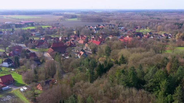 Aerial view of panning at the edge of a forest in front of a typical village in northern germany