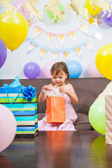 Daughter celebrating a birthday party with unicorn decorations opening gifts