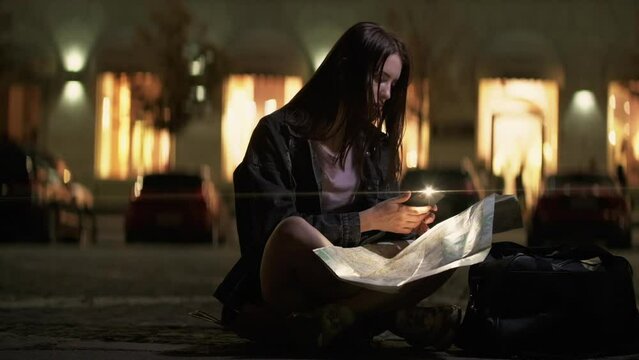 City explorer. Map reading. Trip direction. Pensive mindful young woman tourist searching travel destination way at late night street.