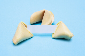 Broken fortune cookies on a blue background and place for text. Mockup. Blank paper for writing a...