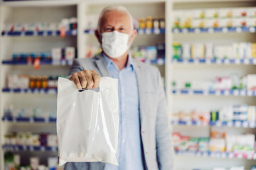 A senior man holding bag with drugs, medicines and vitamins he purchased at pharmacy.