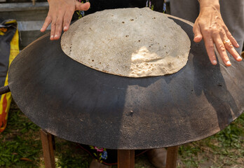Arabian female person prepare flatbread (other names is pita, lavash, lafa, roti, chapati) on hot...