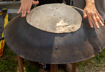 Arabian female person prepare flatbread (other names is pita, lavash, lafa, roti, chapati) on hot...