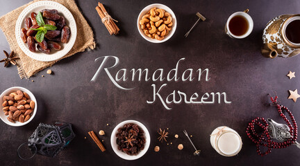 Table top view image of decoration Ramadan Kareem, dates fruit, aladdin lamp and rosary beads on dark stone background.