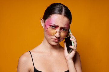 Obraz premium Portrait of beautiful young woman with a phone in hand bright makeup posing fashion emotions close-up unaltered