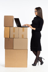 Woman with laptop. Woman business owner. Concept of owner of online store. Business lady works with laptop while standing. Girl with computer on white. Woman preparing boxes for shipping.