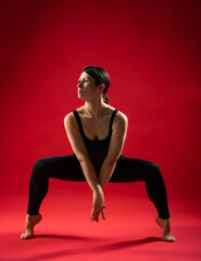 beautiful static poses. pilates on red background Woman in black sportswear. gymnastic poses