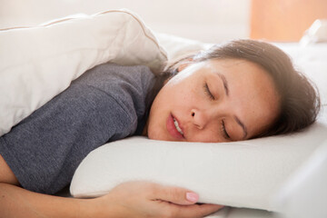 Fototapeta na wymiar woman sleeping on white thin memory foam pillow on white bedsheets in the morning light