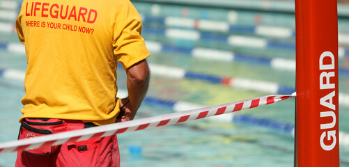 A public pool life guard or pool safety officer in uniform standing duty or guard supervising...