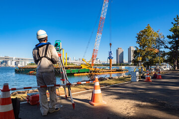 Creation of artificial islands. Geodetic works on artificial territories. Surveyor stands with back...