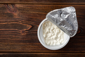 Granulated cottage cheese on dark wooden background.