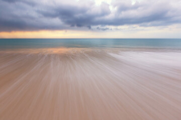 The view of the beach has white foam waves hitting the sand with turquoise water. Fluid dynamics,...