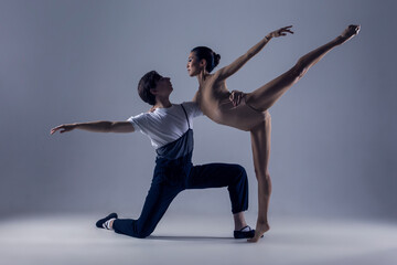 Fototapeta premium Dance Photography. Professional Ballet Dance Couple Performing Together in Studio While Girl Posing in Bodysuit Against White Background.