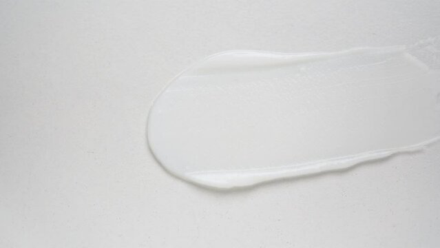 Small metal shovel swipes moisturizing cream over white background upper macro view. Professional cosmetic product for wellness