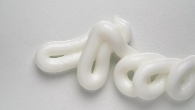 Squeezing moisturizing cream jet from tube onto table upper macro view. Organic cosmetic remedy for professional beauty care