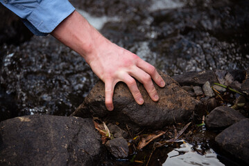 person grabbing a stone near a river