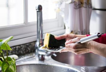 woman washing skimmer in kitchen sink