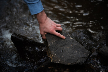 person grabbing a stone near a river