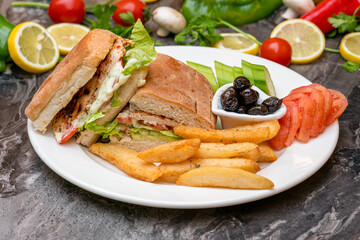 Chicken sandwich on white porcelain plate on dark stone table