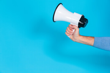 Lifestyle Concepts. Closeup of Hand of Man in Blue Jumper Holding Megaphone Loudspeaker Against Seamless Blue Background.