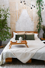 Cozy bedroom with macrame over bed and tea cup, apartment with light interior design in boho chic style © Nastya