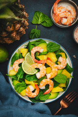 Pineapple salad with shrimps, spinach, avocado and lime on blue stone kitchen table, top view. Healthy eating, balanced, clean diet food, weight loss concept