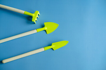 bright green shovel and rake on a blue background top view. Banner. copy spices. flat lay