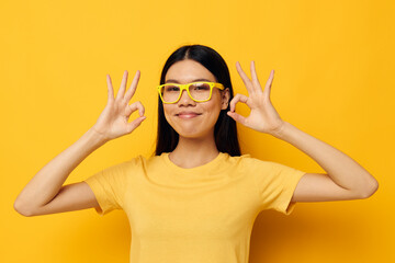woman with Asian appearance in glasses gesturing with hands copy-space yellow background unaltered