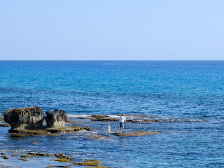 fisherman catches fish on the rocky seashore