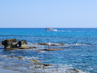 fisherman catches fish on the rocky seashore